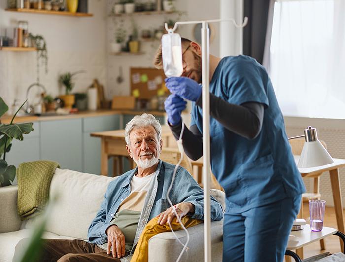 A home health worker adjusts a patient's IV bag