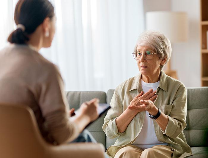 An elderly woman speaks with a female counselor