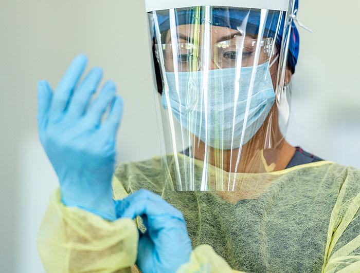A female health worker wearing mask, face shield, latex gloves and other protective equipment