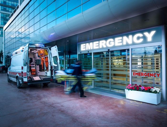 Kaiser Foundation Hospitals emergency department entrance with EMTs bringing a patient in from an ambulance.