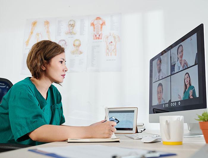 Health worker in virtual consult with four other providers on a screen