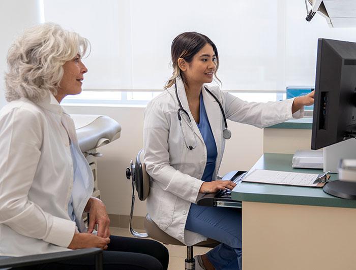 A clinician and a patient sit together looking at a computer screen