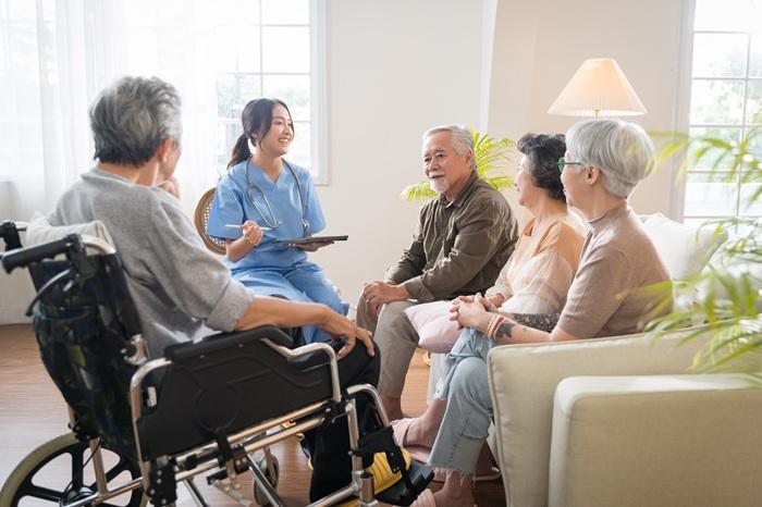 Patients sit in a group speaking with a health worker in scrubs