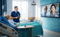 UChicago Medicine to Implement Smart Hospital Platform. A patient in a hospital room has a virtual visit with doctors appearing on a television screen through Artisight's smart hospital platform while a clinician in the room assists.